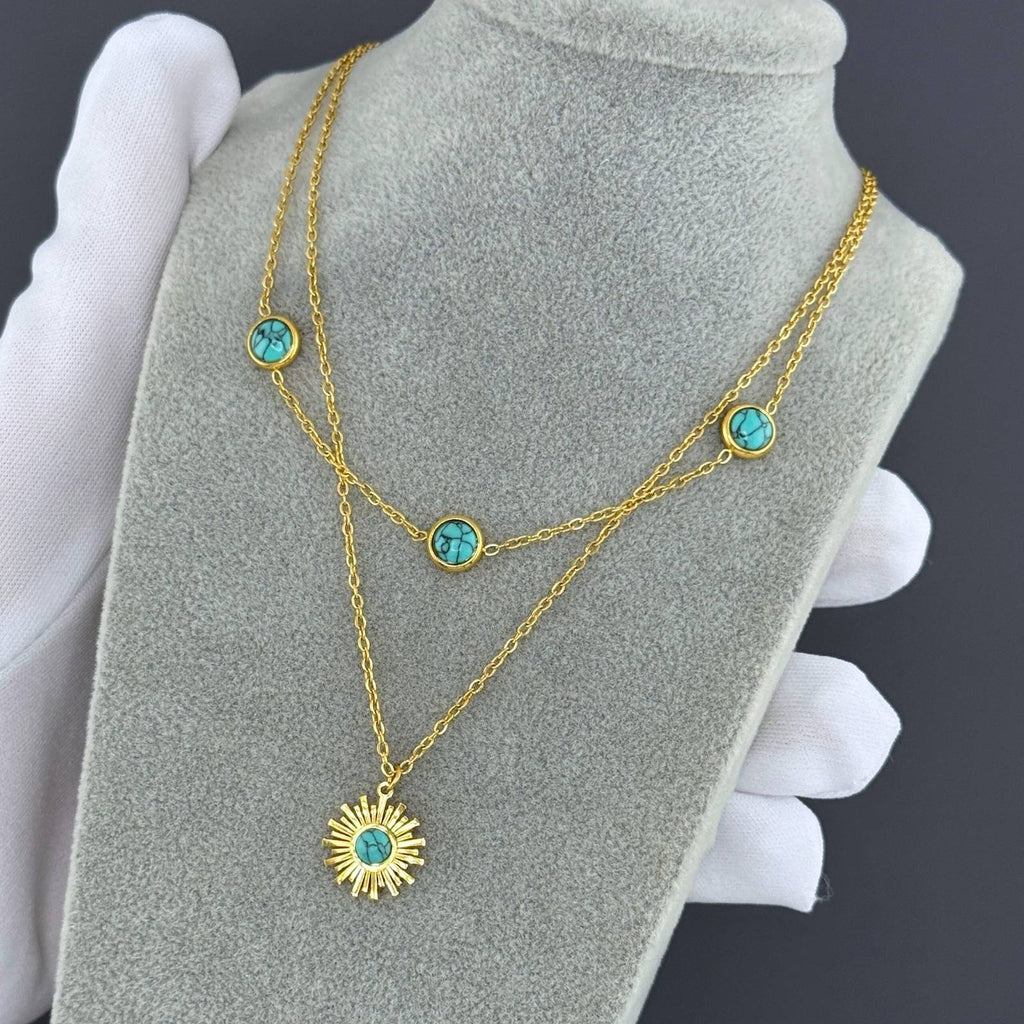 Layered gold necklace featuring turquoise-inspired stones and a sunburst pendant crafted from waterproof hypoallergenic stainless steel.