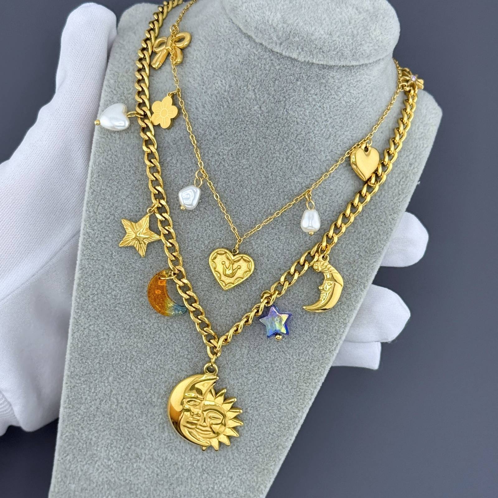 Layered Gold celestial charm necklace featuring sun, moon, and star pendants crafted from waterproof hypoallergenic 18K gold-plated stainless steel.
