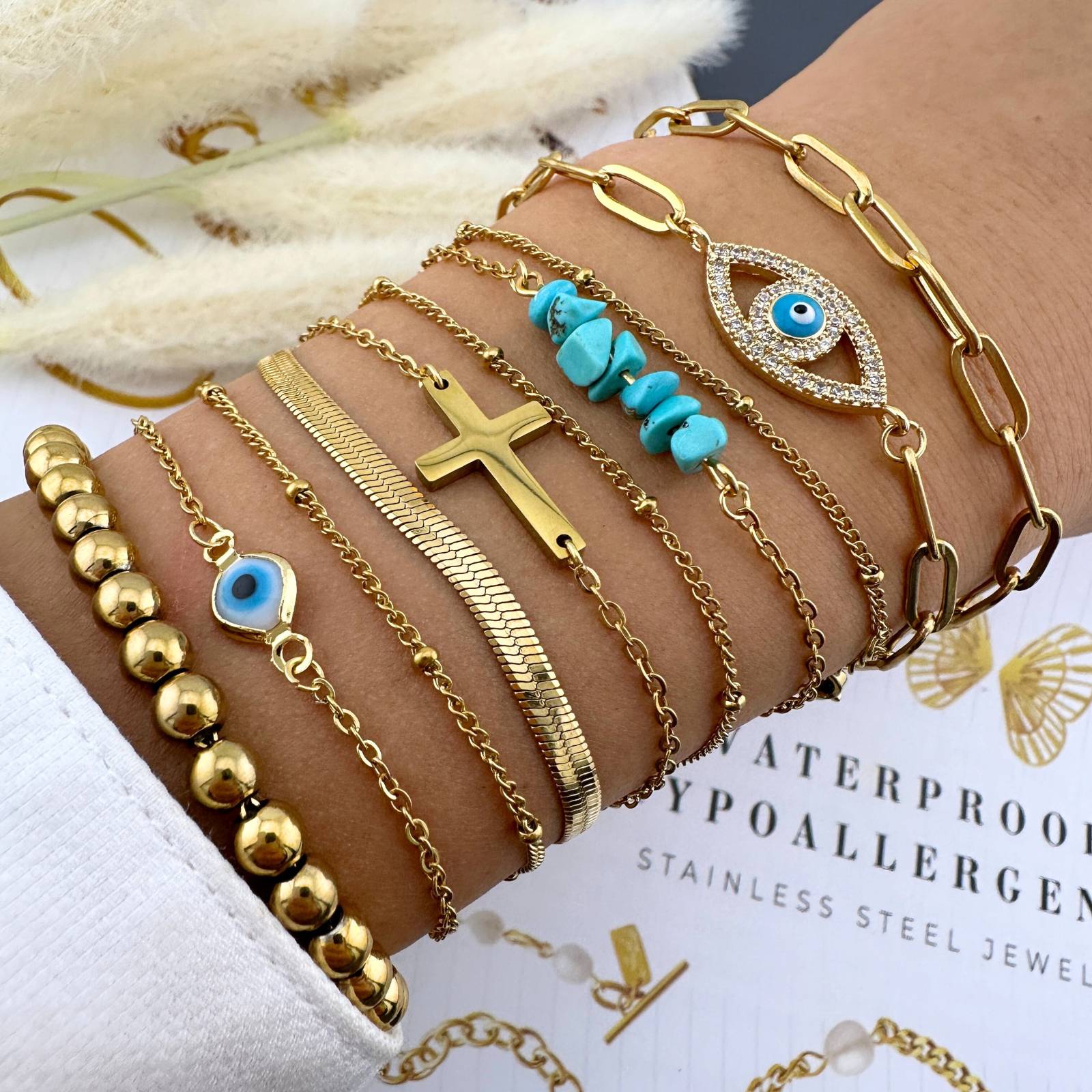 Multiple gold bracelets with various designs including 18K gold plated stainless steel layered bracelet featuring a cubic zirconia evil eye charm and adjustable chain design.