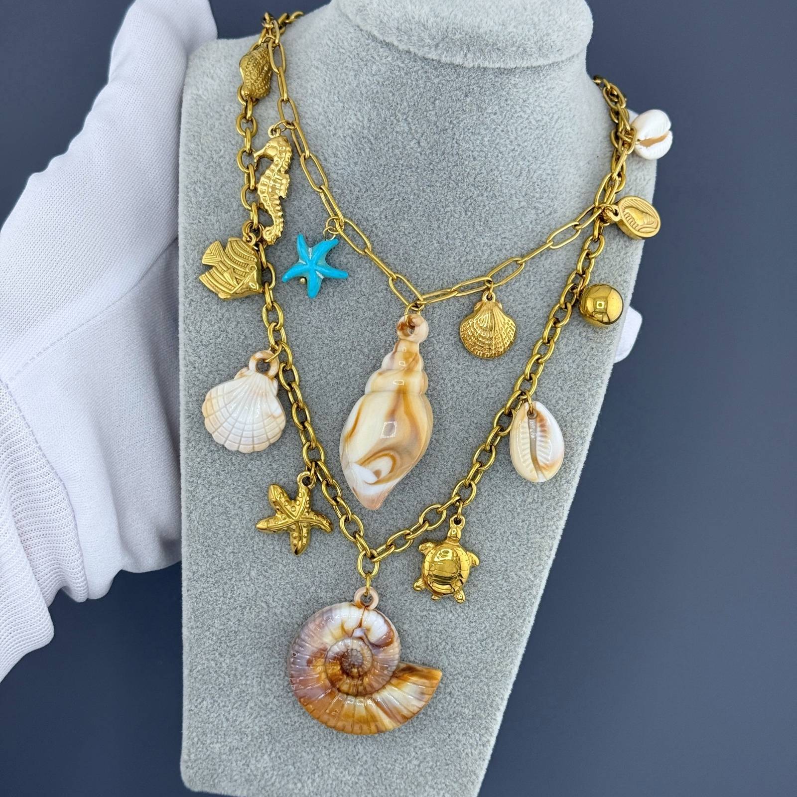 Layered Gold ocean charm necklace featuring a seashell pendant, starfish charm, seahorse charm, and coastal-inspired details crafted from waterproof hypoallergenic stainless steel.