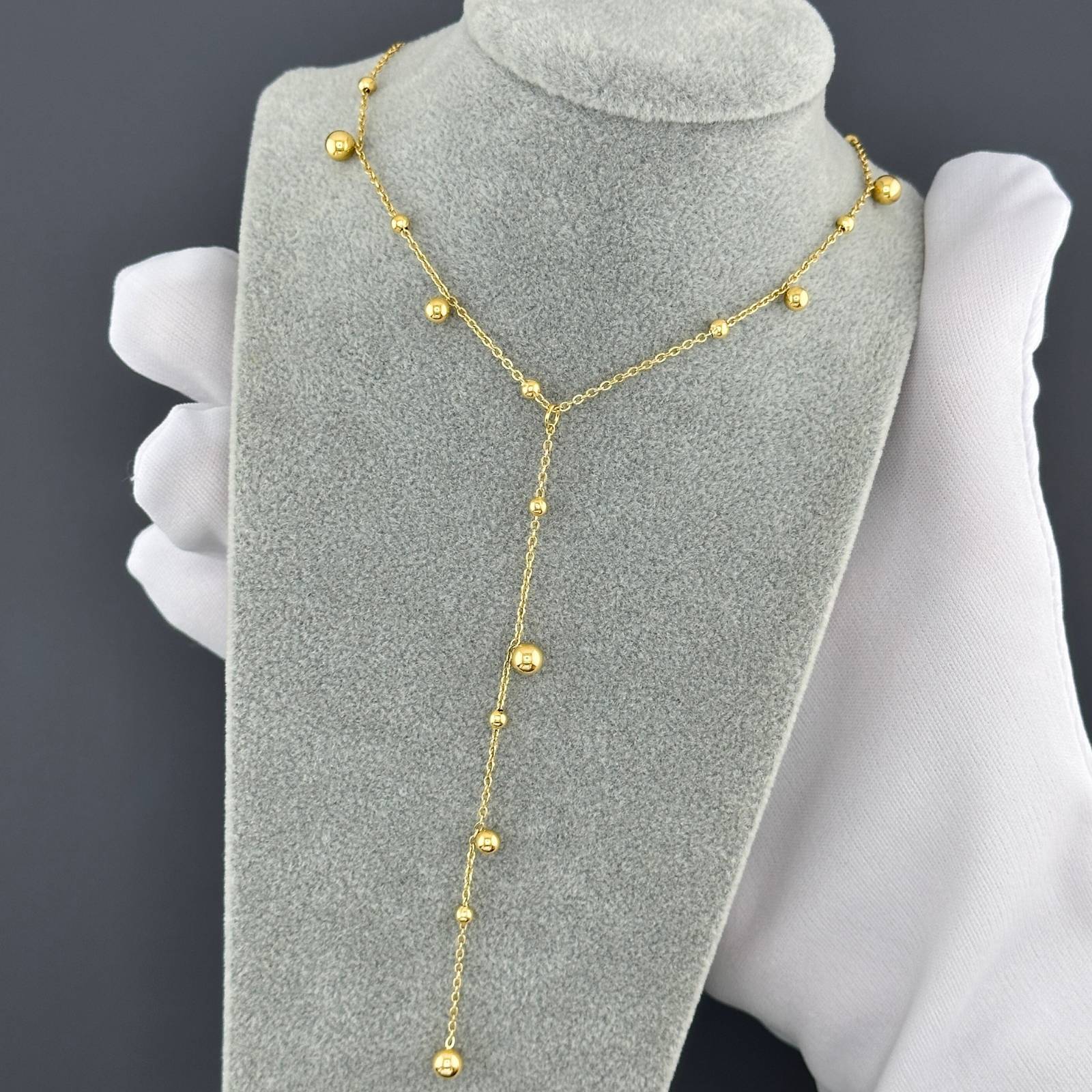 18K gold-plated stainless steel lariat necklace with delicate gold bead accents and cascading drop design.