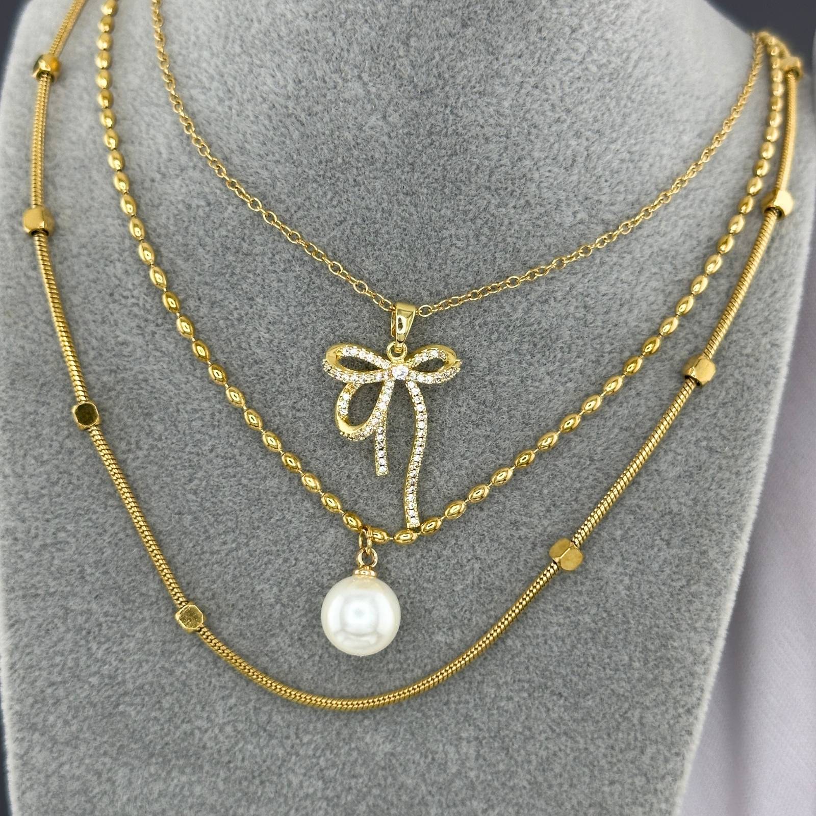 Layered Crystal bow pendant necklace in 18K gold-plated stainless steel with sparkling cubic zirconia stones.