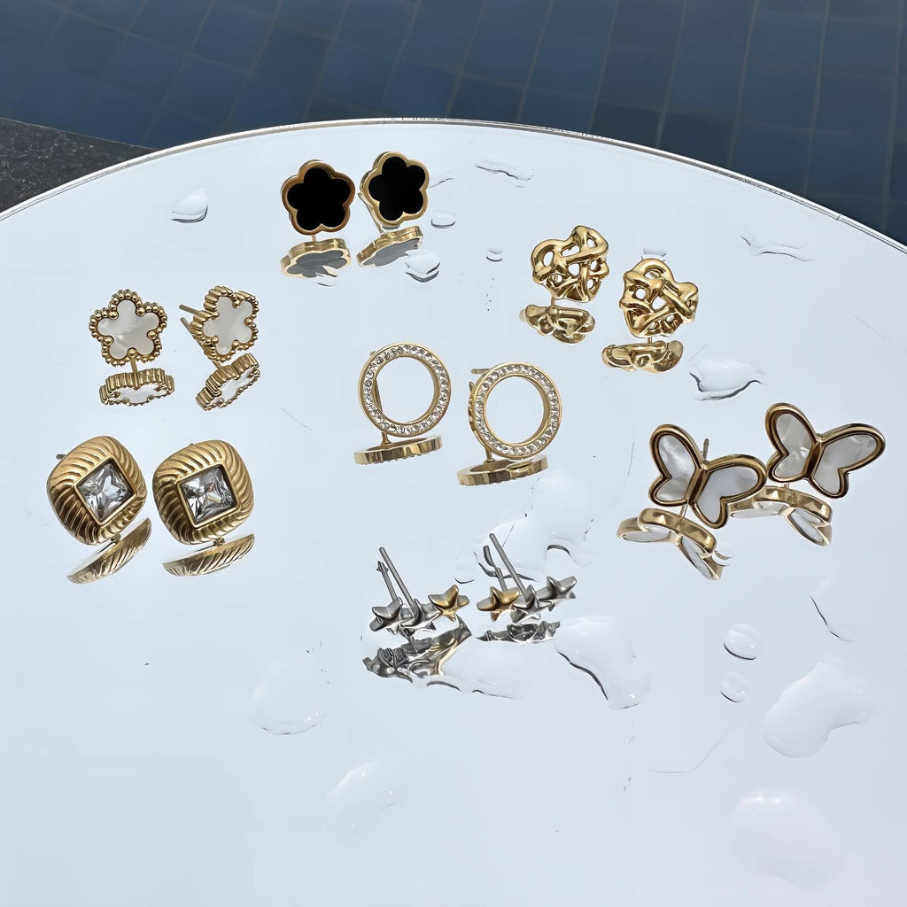 Collection of 18k gold-plated earrings on a mirror.