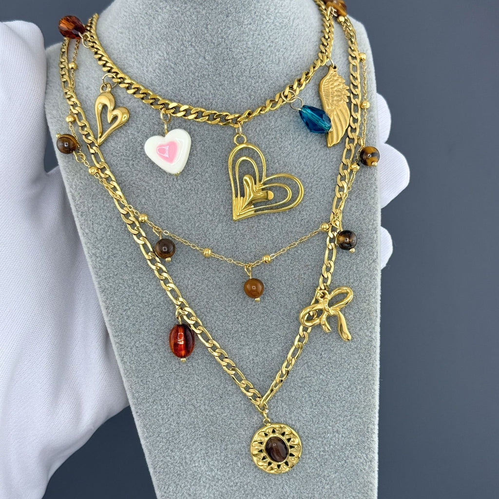 Layered Gold heart charm necklace featuring an angel wing charm, blue crystal accent, and layered heart pendant crafted from waterproof hypoallergenic stainless steel.