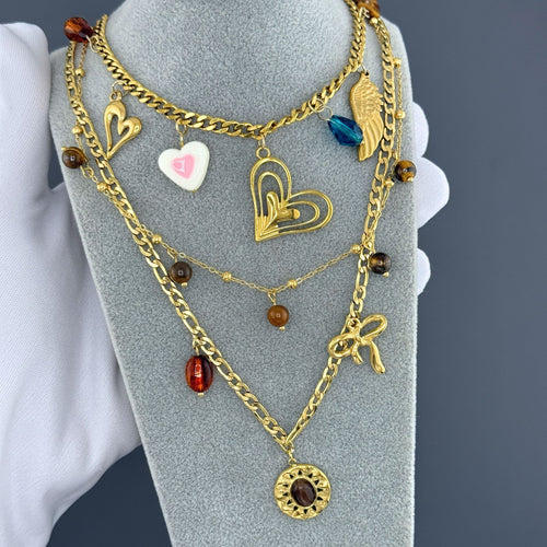 Layered Gold heart charm necklace featuring an angel wing charm, blue crystal accent, and layered heart pendant crafted from waterproof hypoallergenic stainless steel.