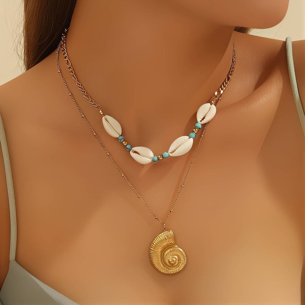 Gold layered necklace featuring a spiral seashell pendant, shell beads, and turquoise accents crafted from waterproof hypoallergenic stainless steel.