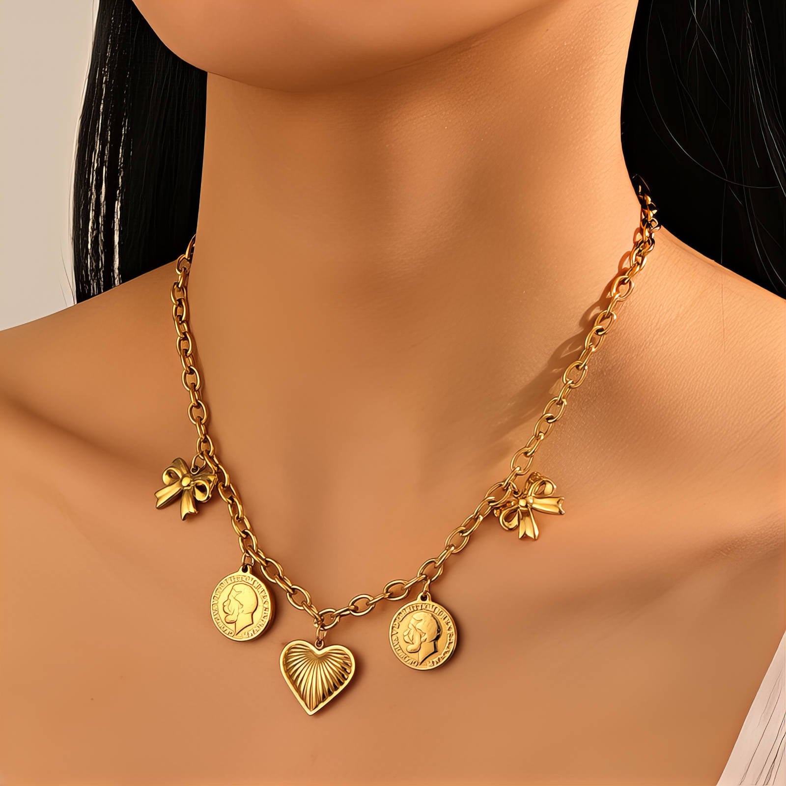 Gold charm necklace featuring a heart pendant, bow accents, and vintage coin charms crafted from waterproof hypoallergenic stainless steel.